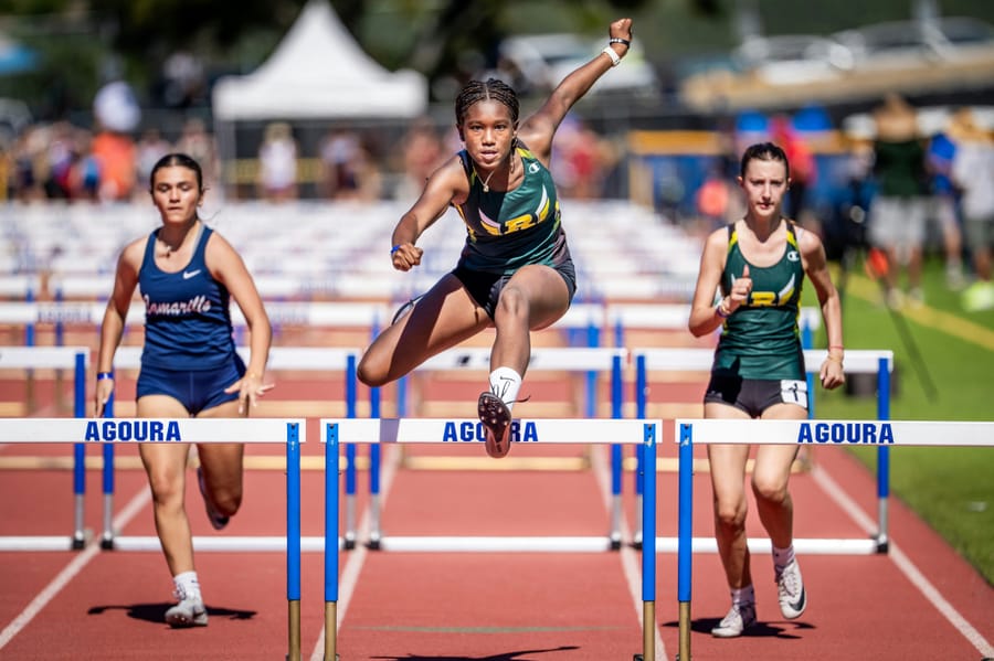 Hurdlers mid-race on an athletics track